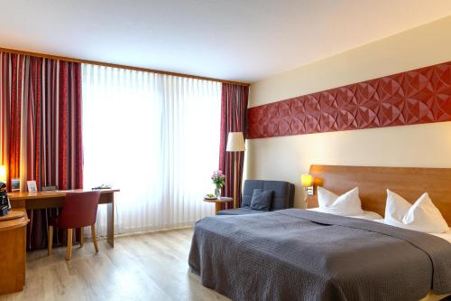 a hotel room with a bed and a desk at Hotel Mercator Itzehoe-Klosterforst in Itzehoe