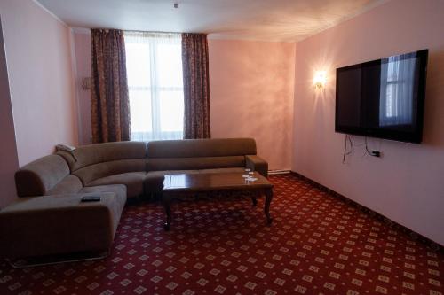 a living room with a couch and a flat screen tv at Silk Way Hotel in Aktau
