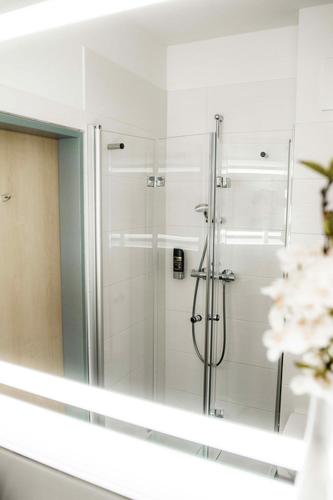 a shower in a bathroom with a mirror at Müritz-Strandhotel in Röbel