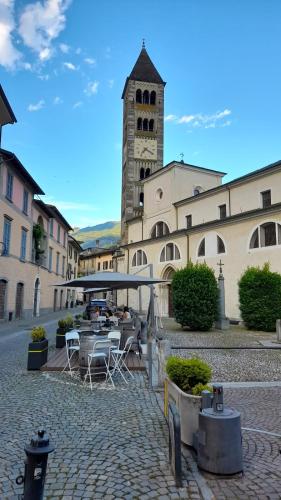 a building with a clock tower with a table and chairs at Loft Tirano centro storico - open space Adele in Tirano