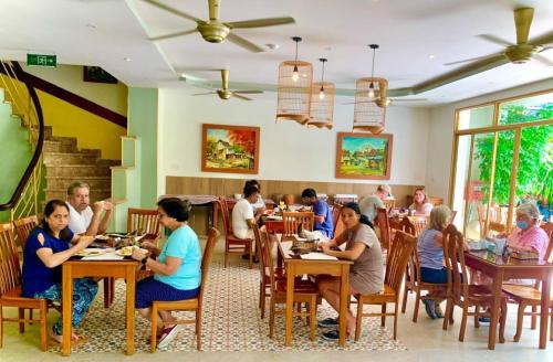 een groep mensen die aan tafels in een restaurant zitten bij De Vivre Hoi An Hotel in Hội An