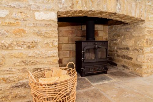 a wood stove in a stone wall with a basket at Farmhouse Retreat, 4 Bed, Pet Friendly in Long Hanborough