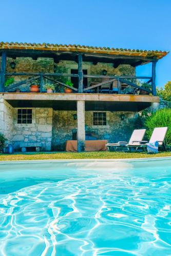 a house with a swimming pool and two white chairs at Just Like Home - Casa do Cadinho in Viana do Castelo