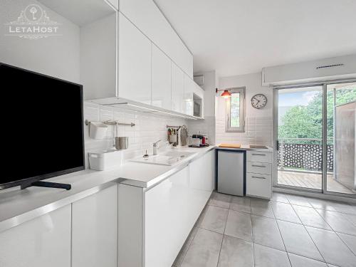 une cuisine avec des armoires blanches et une télévision à écran plat dans l'établissement Balcon Montpelliérain proche Fac et Hopitaux, à Montpellier