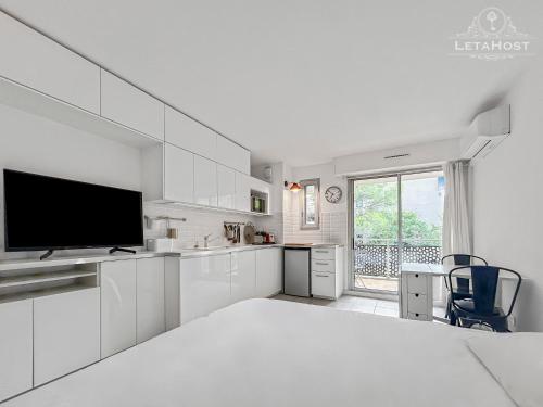 une cuisine blanche avec un grand lit et une télévision dans l'établissement Balcon Montpelliérain proche Fac et Hopitaux, à Montpellier