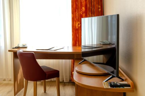 a desk with a computer monitor and a chair at Hotel Mercator Itzehoe-Klosterforst in Itzehoe