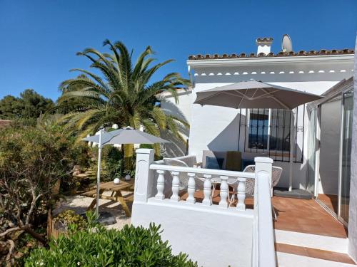 a white house with a porch and umbrella at Villa Estrella de Mar in Moraira