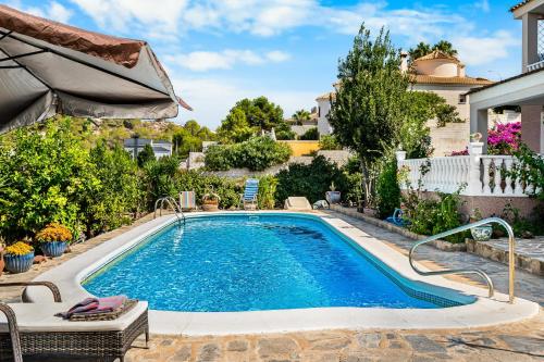 a swimming pool in a yard with an umbrella at Casa Starlite Sunrise in Almoradí