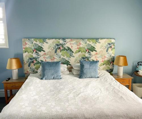 a bedroom with a bed with two lamps and two pillows at Mere Brook House in Wirral