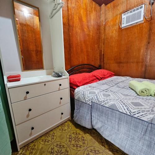 a bedroom with a bed and a dresser with a mirror at Casa Celine Dumaguete in Dumaguete