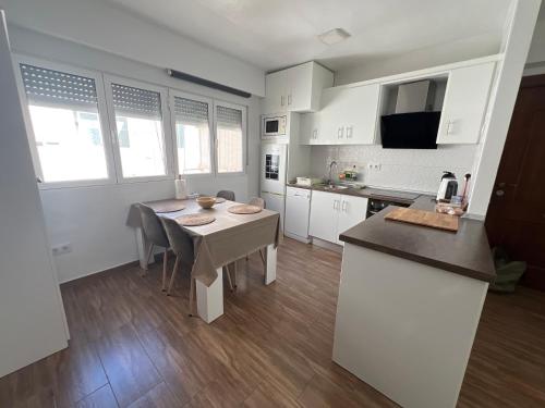 cocina con mesa y cocina con armarios blancos en Brisa & Beach a 3 Min de la Playa Zapillo, en Almería