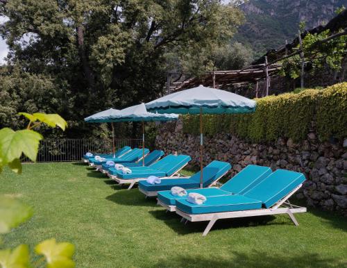 a row of blue lounge chairs with umbrellas at Villa Torre in Erchie