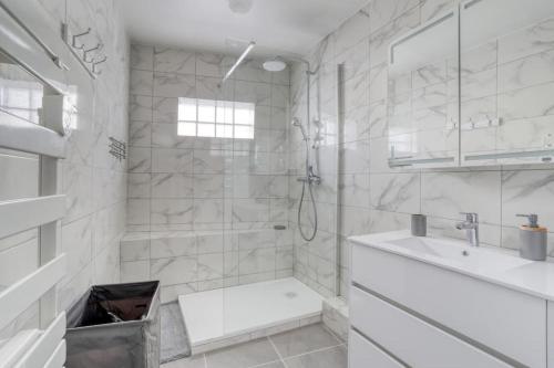 une salle de bain blanche avec une douche et un lavabo dans l'établissement Badalux - Paris, CDG, Expo Parc, StadeDeFrance, à Aulnay-sous-Bois