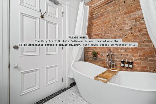 a bathroom with a white bath tub next to a brick wall at The CAPE in Picton