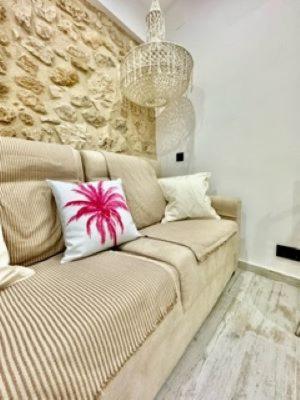 a couch in a living room with a stone wall at La Esquina 1B in Denia