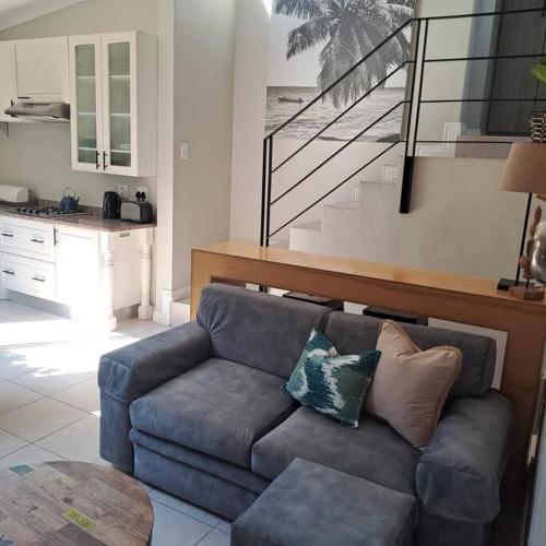 a living room with a blue couch and a kitchen at Open, Fresh & Private - Loft Styled Apartment in Durban