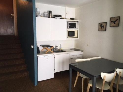 une cuisine avec des armoires blanches, une table et un micro-ondes dans l'établissement Studio cosy 4 pers, centre station, proche pistes et commerces - FR-1-404-51, à La Mongie