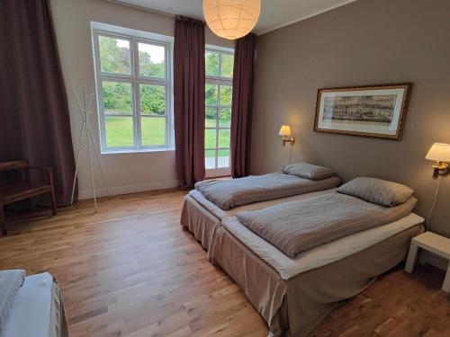 two beds in a room with two windows at The Old Vicarage in Rødby