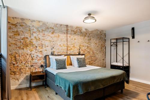 a bedroom with a bed and a brick wall at Boetiekhotel Ons Oude Raadhuis in Hooge Zwaluwe