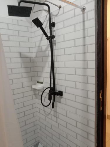 a shower in a bathroom with a white brick wall at Compass Homestay in Huu
