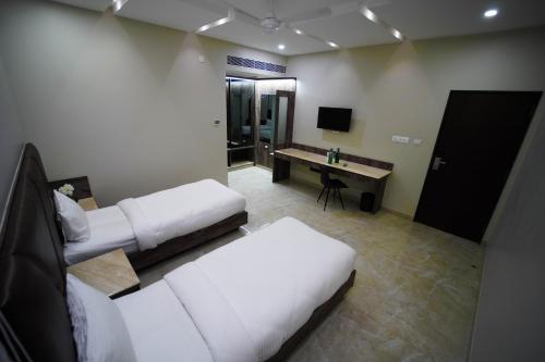 a hotel room with two beds and a desk at Sun Shine Hotel in Bengaluru