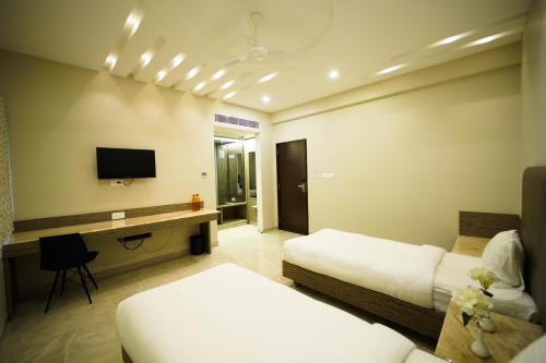 a hotel room with two beds and a television at Sun Shine Hotel in Bengaluru