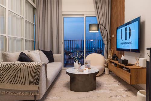 a living room with a couch and a tv at Dubai Hills - 1BR Luxe Apartment - Golfville - by UDH in Dubai