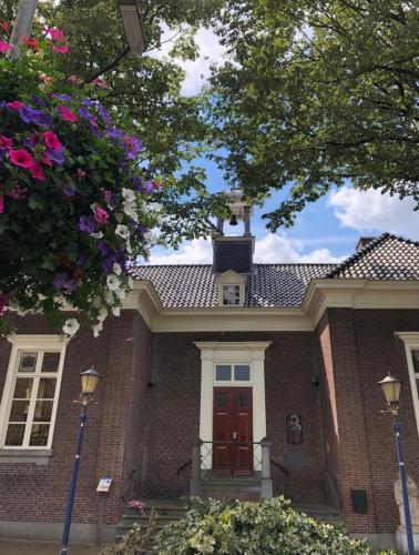 a red brick house with a red door and flowers at Boetiekhotel Ons Oude Raadhuis in Hooge Zwaluwe