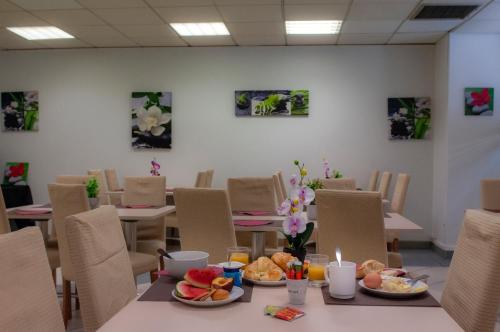 a dining room with tables and chairs with food on them at Appart'hôtel Goélia Sun City in Montpellier