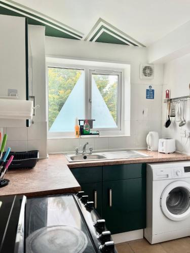 GoodmayesにあるThe Express Apartmentのシンクと洗濯機付きのキッチン