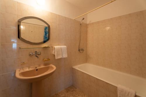 a bathroom with a sink and a tub and a mirror at Хотелски комплекс Ямболен in Tŭrnava