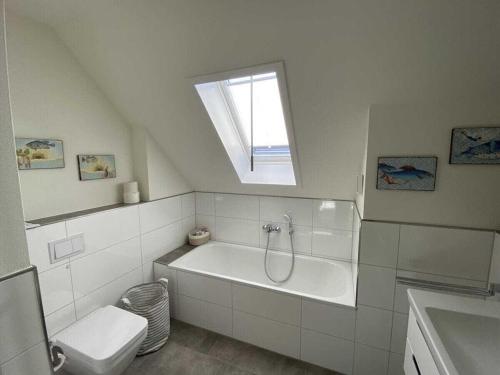 a bathroom with a tub and a toilet and a window at Holiday home Ankerherz in Butjadingen