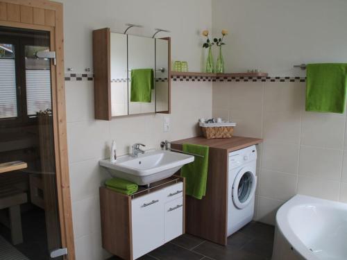a bathroom with a sink and a washing machine at Luxury holiday house "Schleibrise" in Hestoft