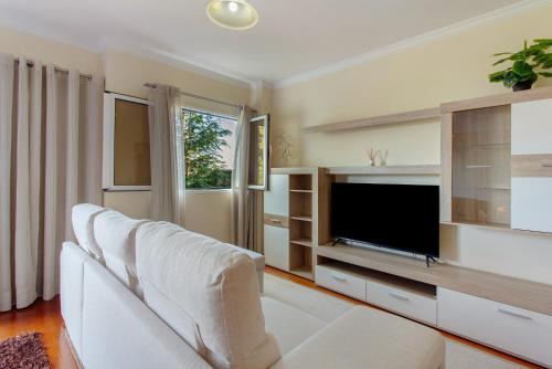 a living room with a white couch and a flat screen tv at Refugio Dourado in Água de Pena