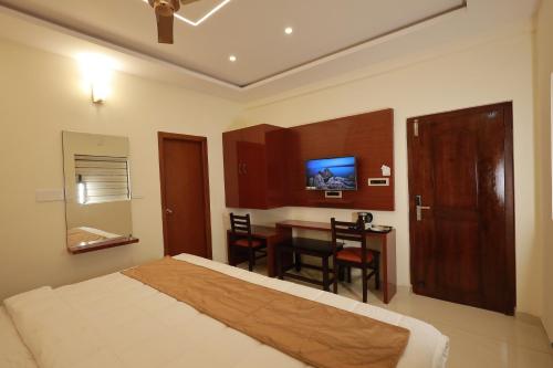 a bedroom with a bed and a table and a television at Swami Prasad Paradise hotel in Golitattu