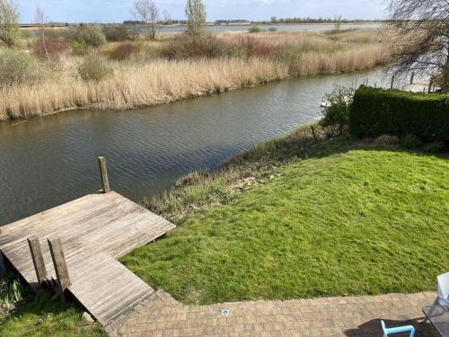 a wooden dock on the side of a river at Beachvilla Grachtenblik in Makkum