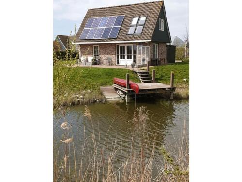 a house with a dock and a boat in the water at Beachvilla Grachtenblik in Makkum