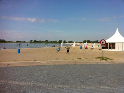 a beach with people playing in the sand and a white tent at Beachvilla Grachtenblik in Makkum