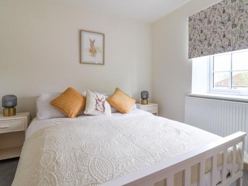a bedroom with a white bed with pillows and a window at Belfry Cottage in Colyton
