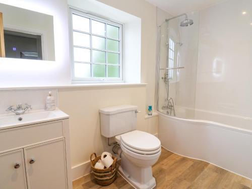 a bathroom with a toilet and a tub and a sink at Belfry Cottage in Colyton