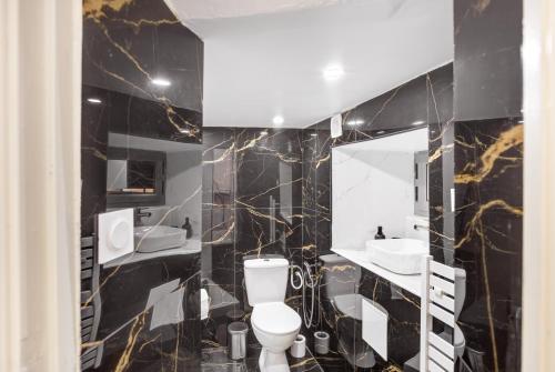 - une salle de bains en noir et or avec toilettes et lavabo dans l'établissement Escapade Grassoise, à Grasse