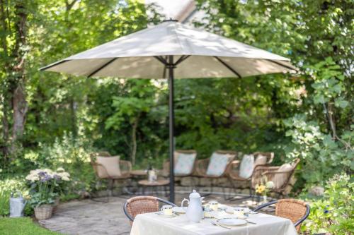 a table with an umbrella in a garden at Villa Benz Hotel garni in Schwetzingen