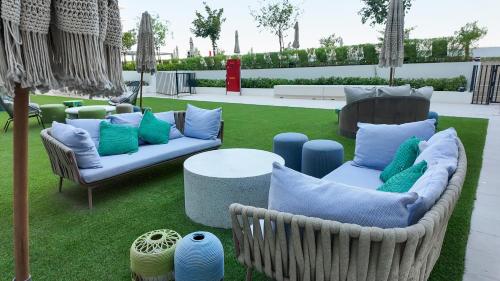 a patio with two couches and a table with pillows at Dubai Hills - 1BR Luxe Apartment - Golfville - by UDH in Dubai
