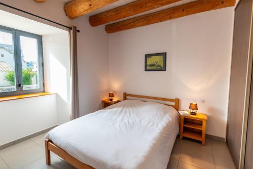 a bedroom with a white bed and a window at Gîte Gîte de France 6/10 personnes à La Ferme Lionnet in Albaret-le-Comtal