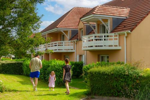 a man and two children walking in front of a house at Résidence Goélia Les Portes d'Honfleur in Boulleville