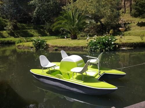a green and white boat with two chairs on the water at Hostería el Socavón in Guaranda