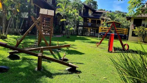 a playground in a yard with wooden swings at Apartamento com varanda em frente a Praia de Maresias in São Sebastião