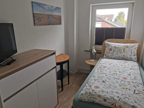a small bedroom with a bed and a television at Strandhaus Deichvoigt in Cuxhaven
