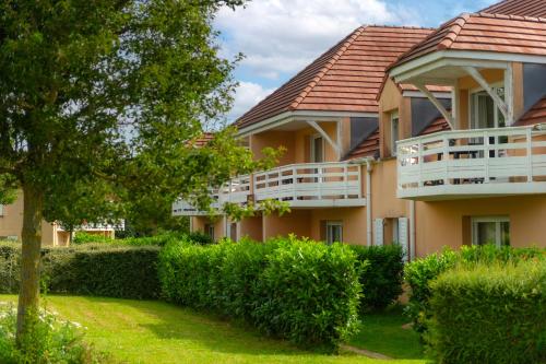 a large apartment building with a balcony and bushes at Résidence Goélia Les Portes d'Honfleur in Boulleville
