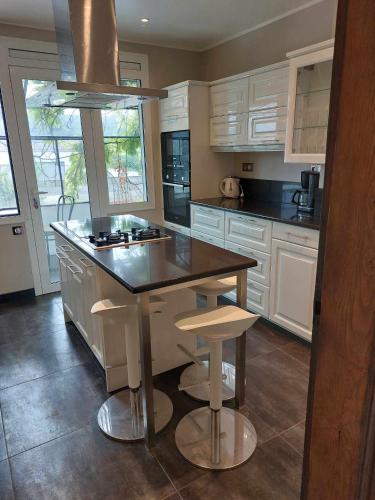 une cuisine avec des armoires blanches et un îlot avec des tabourets dans l'établissement L'ABulle glanoise, à Gland